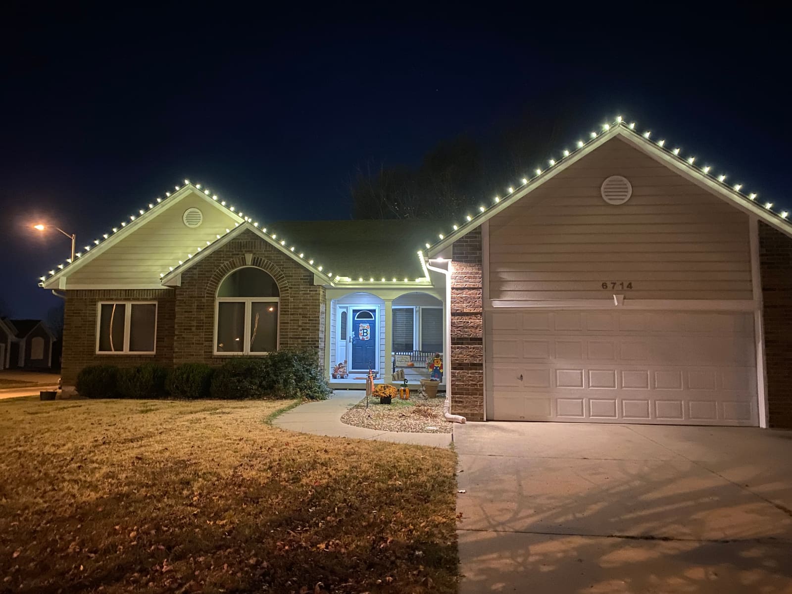 Brick ranch home with warm white Christmas lights tracing every roofline and gable